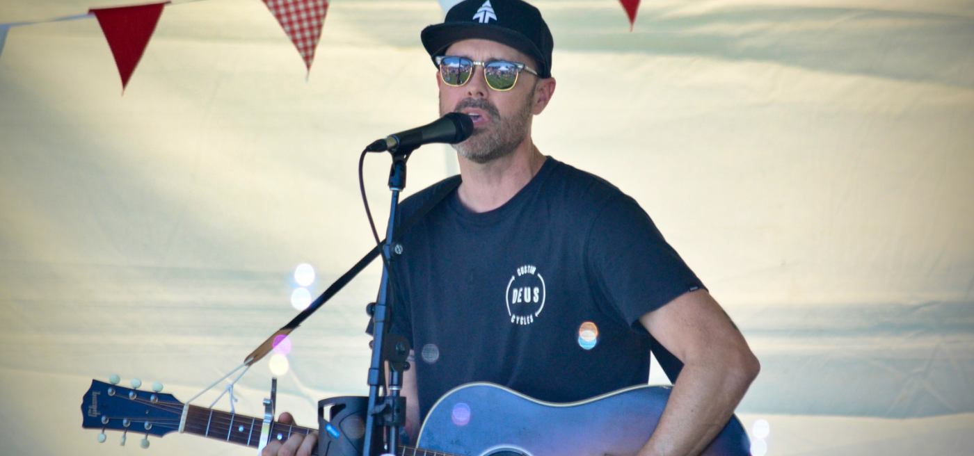 man singing and playing guitar on a stage