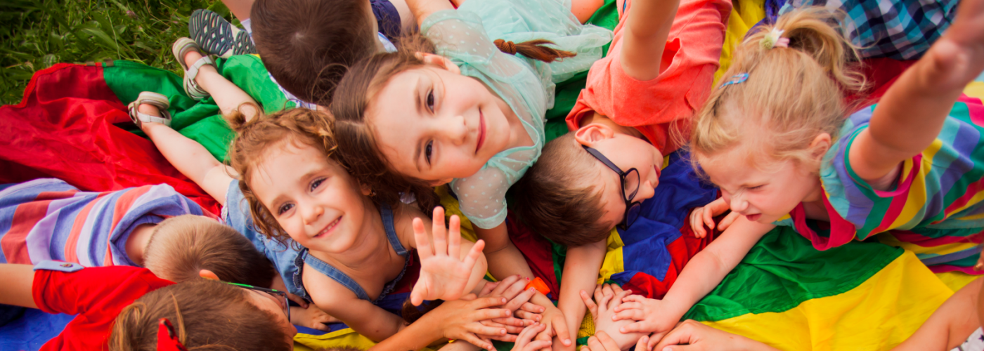 children lying in the grass and looking up at camera