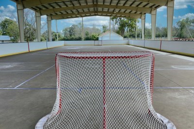 concrete pad with a roof with hockey nets and basbetball hoop