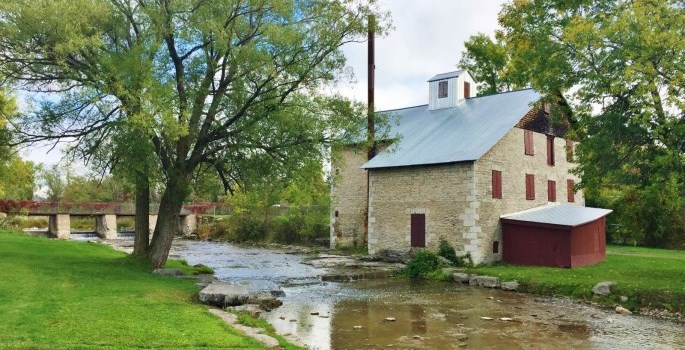 stone building beside a stream with a bridge