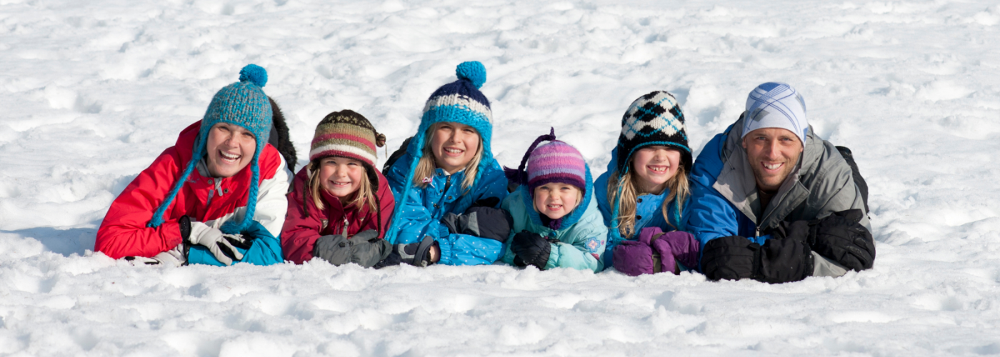 family in winter clothes posing in a line in snow