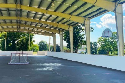 concrete pad with a roof with hockey nets and basbetball hoop
