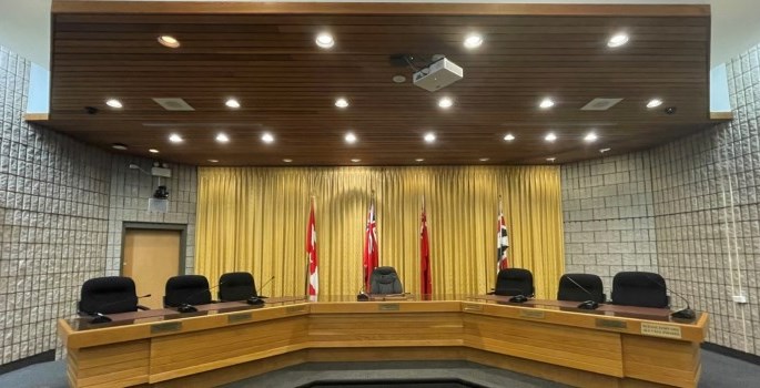 seats at a table in municipal chambers