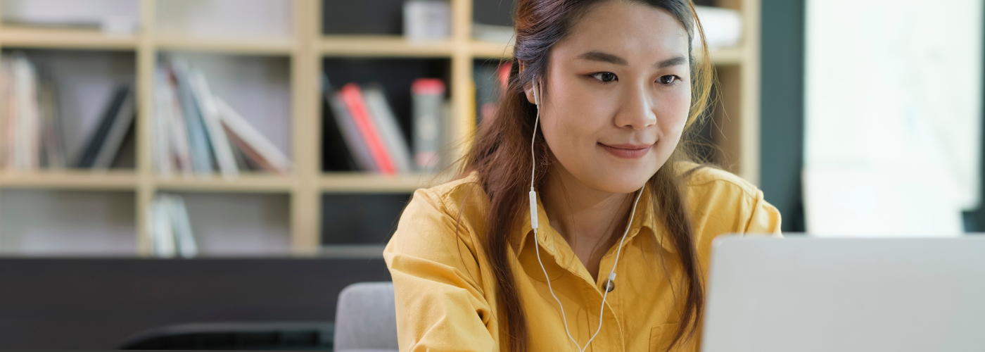 Woman wearing earbuds while looking at laptop screen