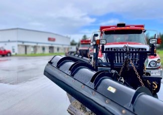 red snow plow parked on wet paving